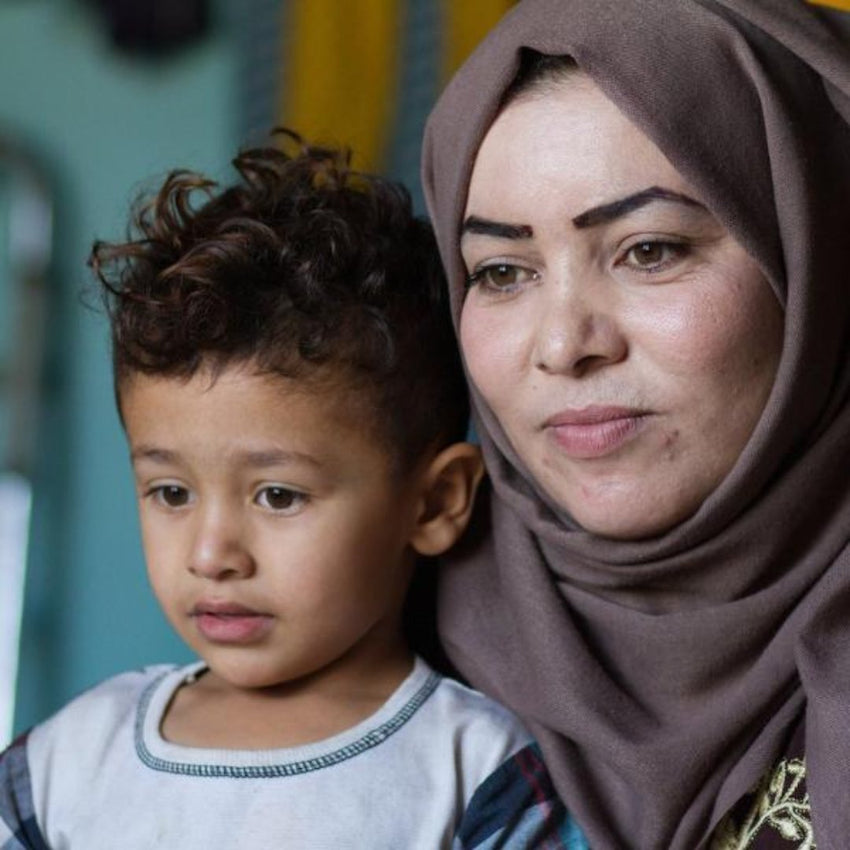 Woman holding son in house
