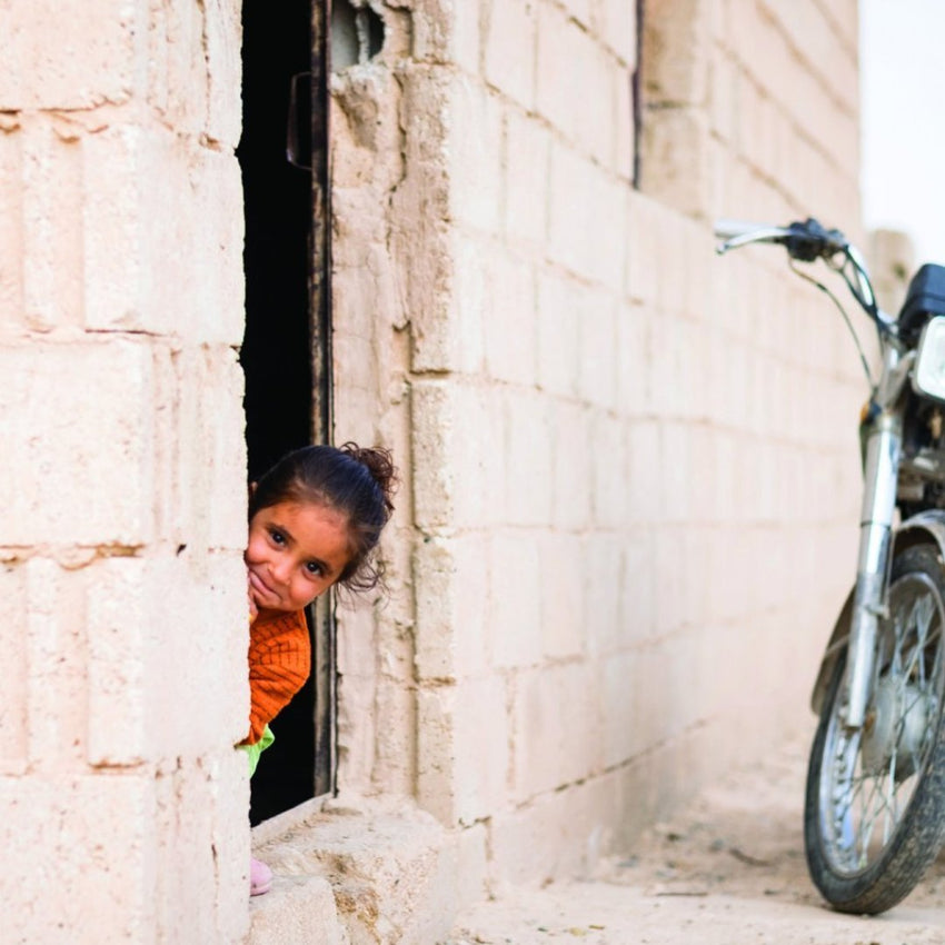 smiling refugee child peeping out of a prefabbed house 